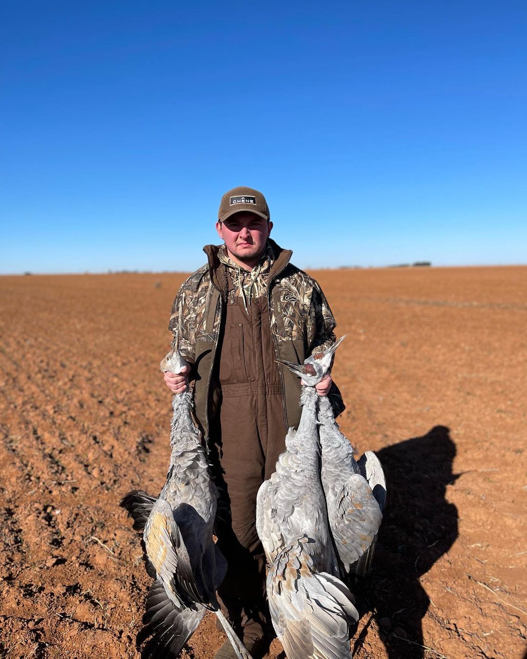 Man hunter holding three deceased cranes