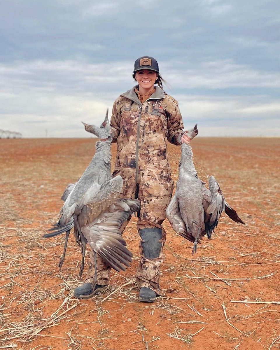 Woman hunter holding deceased cranes after being hunted