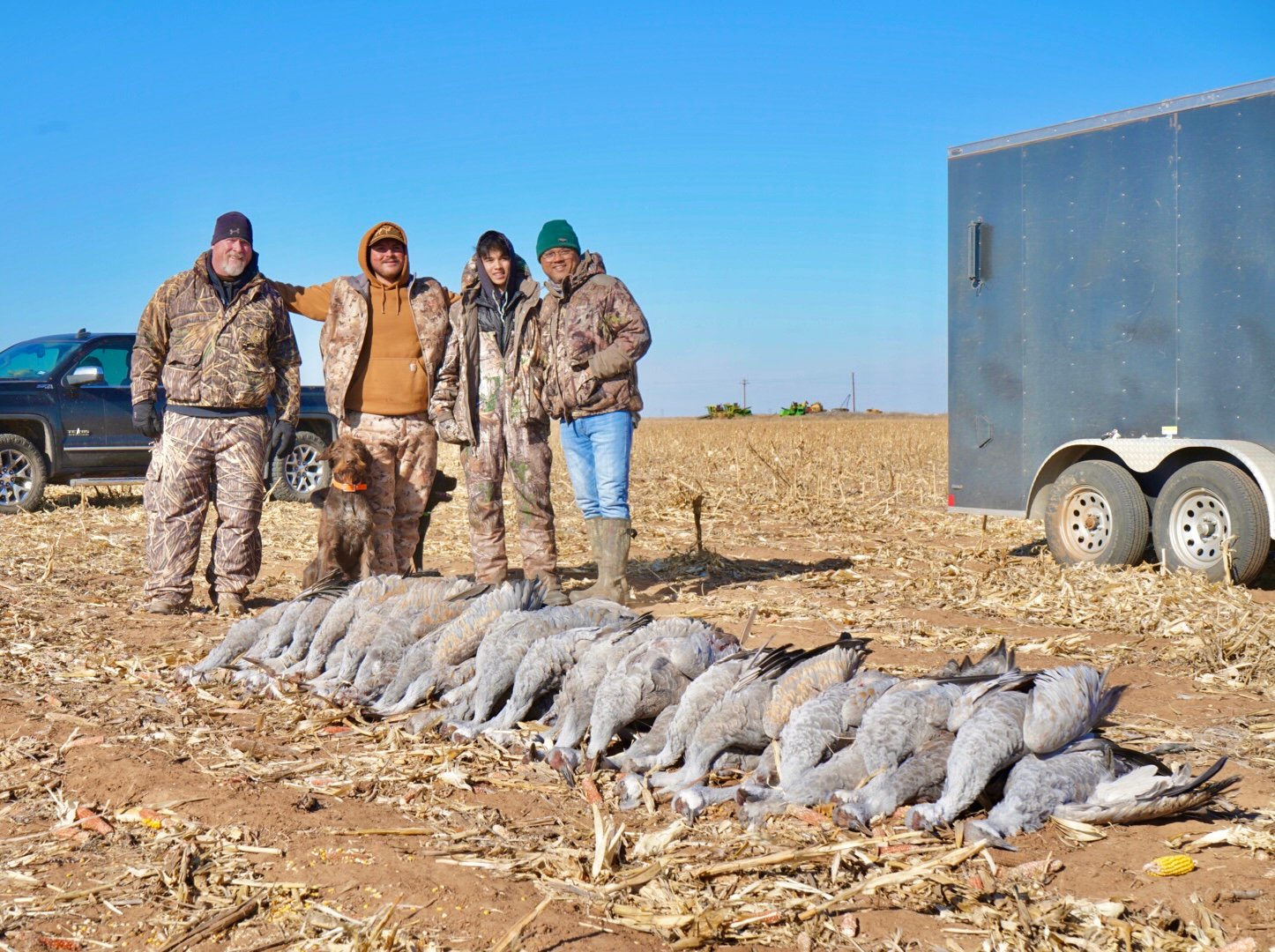 Group of hunters with their hunting dog and deceased sandhill cranes