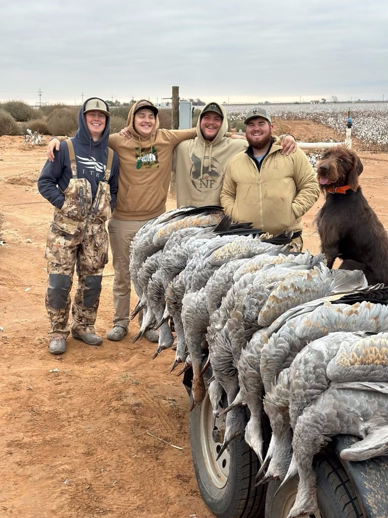 Group of hunters with their hunting dog and deceased sandhill cranes