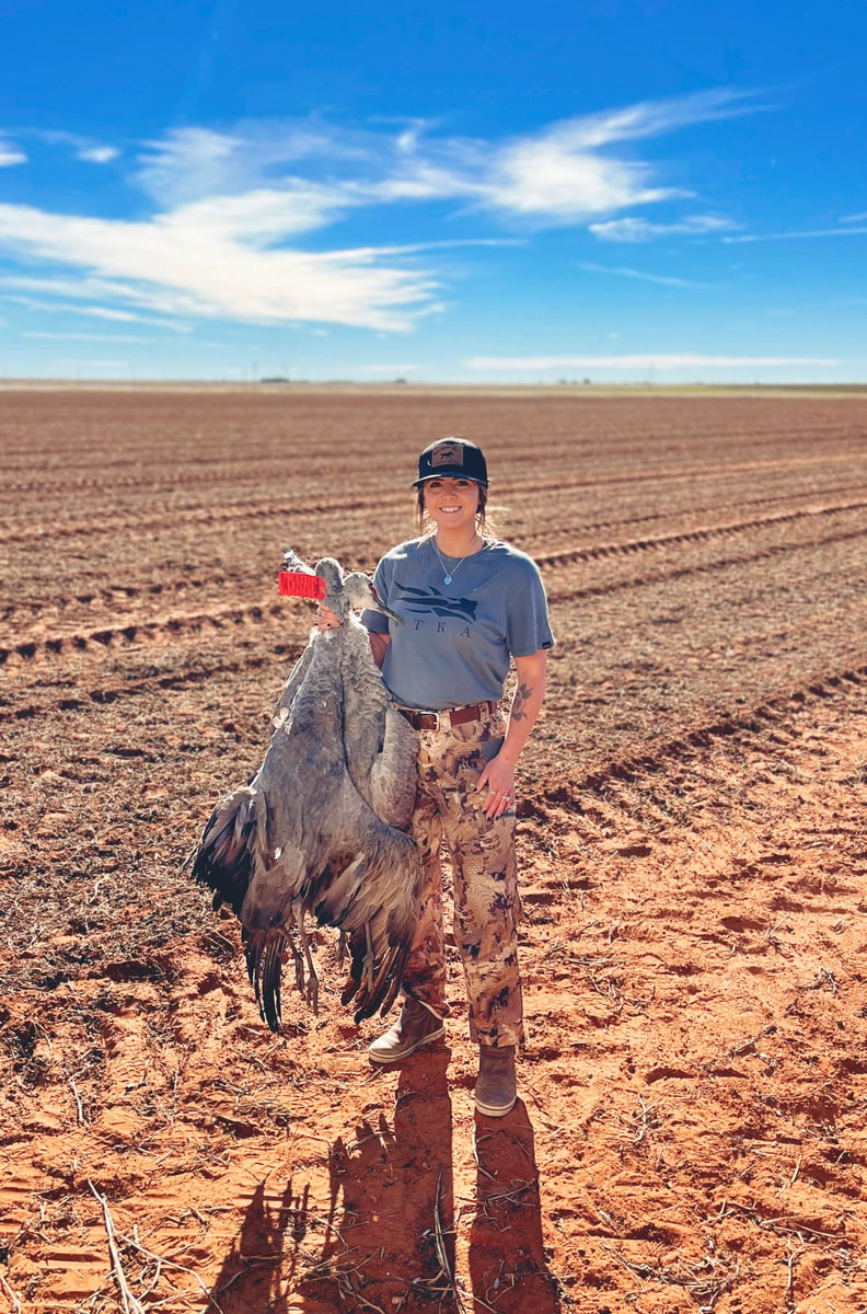 Woman hunter in Lubbock, TX field with sandhill crane