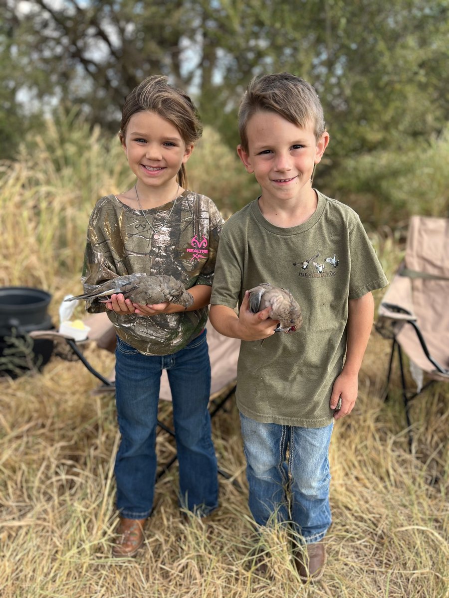 Boy and girl hunters holding deceased doves