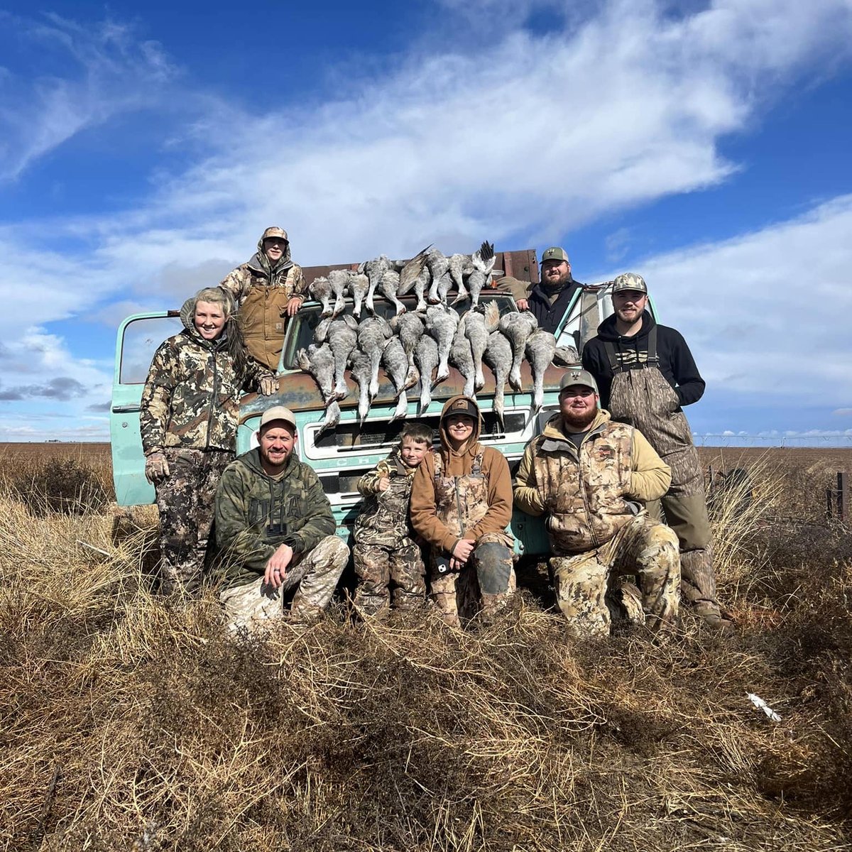Group of hunters with sandhill cranes in front of blue truck